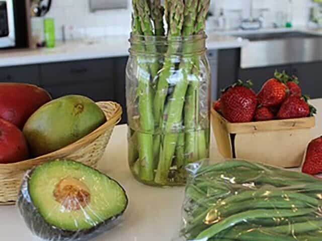 Avocado, asparagus, green beans, mango and strawberries on kitchen counter