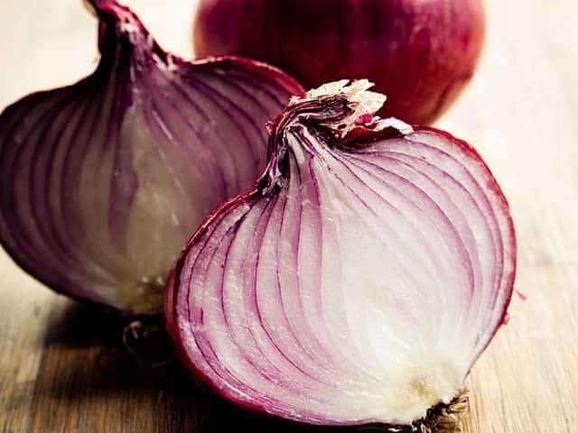 Red Onion cut in half with whole red onion in background