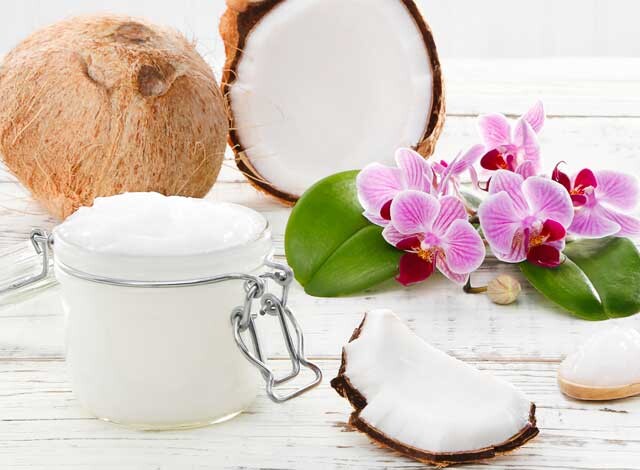 coconuts with coconut oil & flowers on white wood table