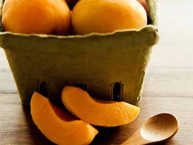 Apricots in a carton behind wooden spoon