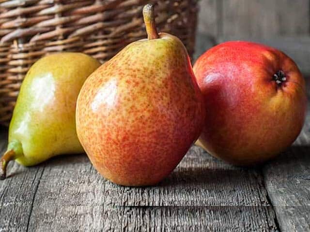 Three Pears on brown wood in front of basket