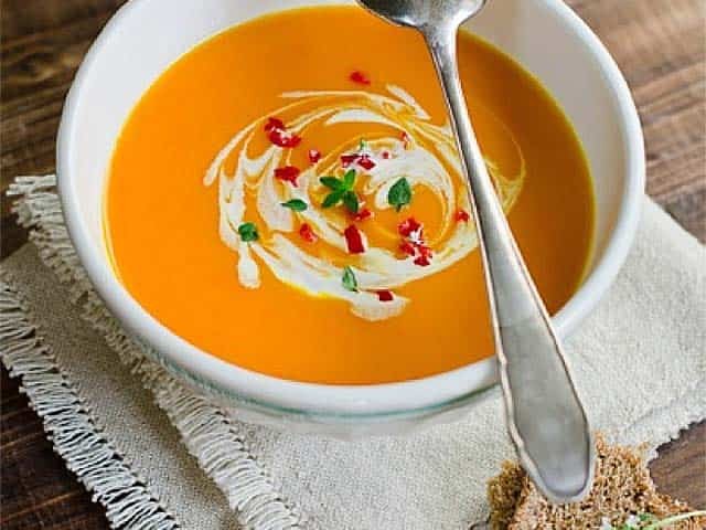 Bowl of pumpkin soup on place mat with bread