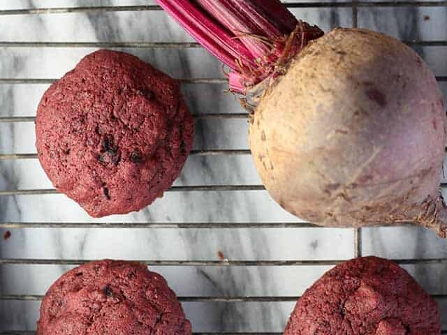 chocolate chip beet cookies on rack surrounding a fresh beet