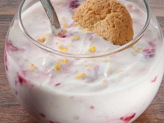 strawberry cheesecake yogurt in glass bowl with cookie and spoon