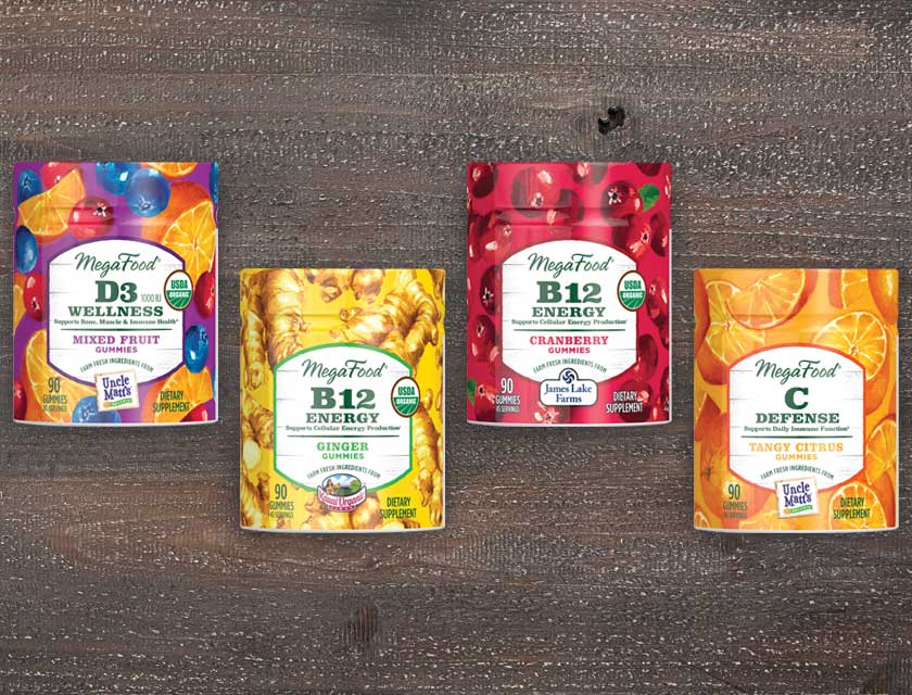 four bottles of MegaFood gummies on a wood background