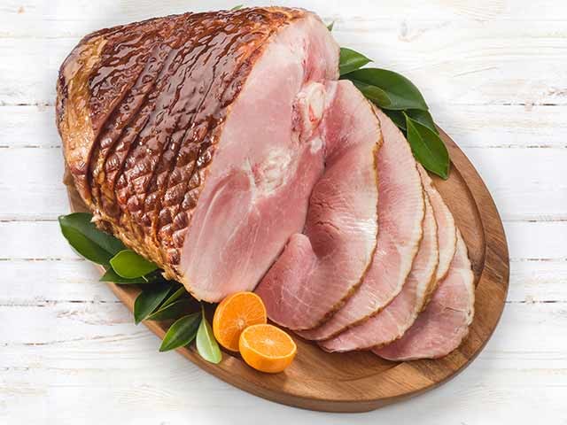 Spiral ham on platter with oranges and herbs