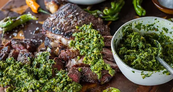 Ribeye Steak on a cutting board next to Shishito Pepper sauce