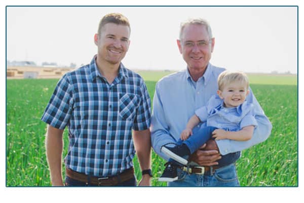 Farmer, son and grandson in field.