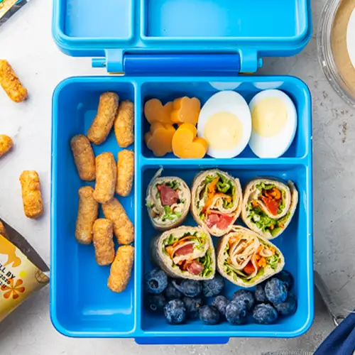 Peanut butter puffs, hard boiled eggs, and veggie rolls in a bento box