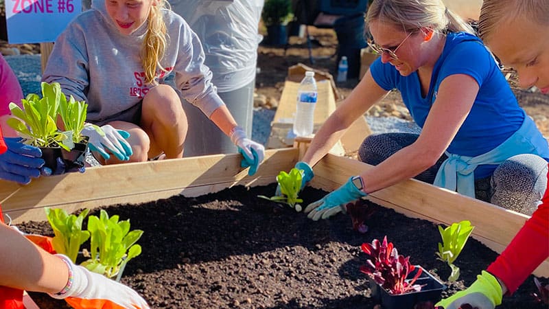 teacher working with students in a garden