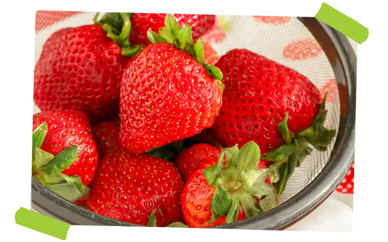 strawberries being washed in a colander